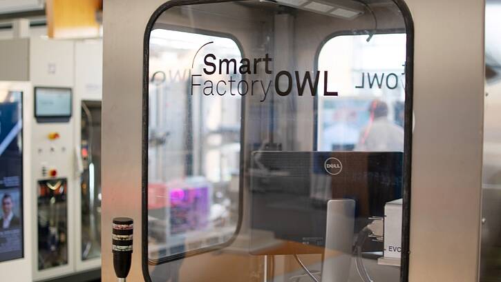 Eine Tür zu einem elektrotechnischen Prüfraum. Auf dem Glas an der Innenseite der Tür steht: "Smart Factory OWL"